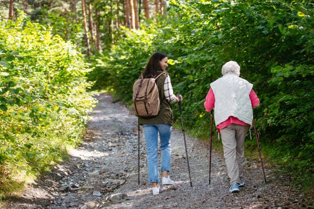 IMAGO Creative, Ostern, Bräuche, Osterspaziergang #2 Senior woman and daughter enjoying hike with trekking poles. Senior woman and daughter enjoying hike with trekking poles. Nordic walking in forest. model released