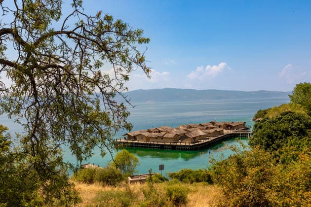 Stilted village of thatched huts over turquoise water with mountains in the distance Copyright: LauraxGrier 1218-2136
