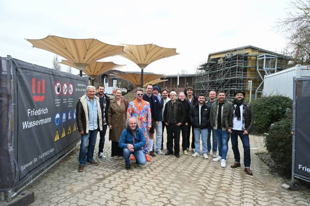 Gruppenbild der Bands und Veranstalter der autretenden Künstler posieren bei der Programm PK vor der Baustelle des Kölner Tanzbrunnen der nach umfangreicher Sanierung pünktlich zu Saisonstart am 09.05.2026 fertig sein soll