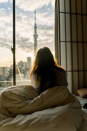 Woman Looking Out from Bed at Tokyo Sky Tree During Sunrise Tokyo, Tokyo, Japan CR_DVQR260317-1982942-01 ,model released, Symbolfoto