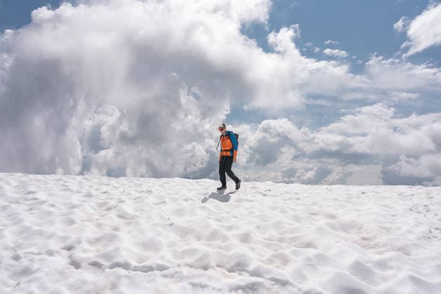 Hiker crossing a patch of snow in the mountains Urtijëi, Trentino-South Tyrol, Italy CR_MIJO260317DD-1984921-01 ,model released, Symbolfoto
