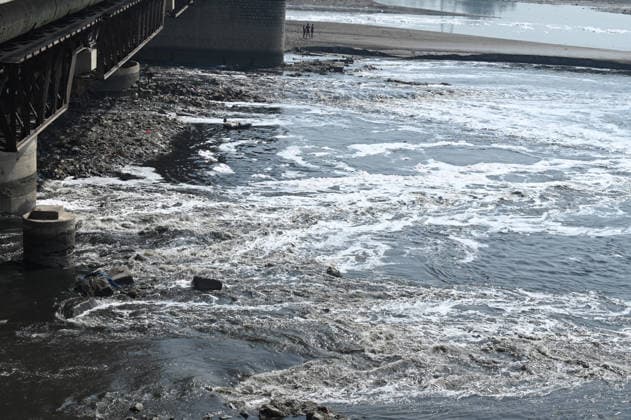 NEW DELHI, INDIA - MARCH 18: Toxic white foam seen floating in the Yamuna river at Chhath ghat ITO on March 18, 2026 in New Delhi, India. The foam is composed of surfactants, detergents, and industrial pollutants, which create a thick, foul-smelling layer. Despite various clean-up efforts, 3,500 million liters of municipal sewage and industrial waste are dumped daily, with Delhi responsible for 76 percent of the river s total pollution. (Photo by Sonu Mehta Hindustan Times) Water Pollution In Yamuna River At Delhi