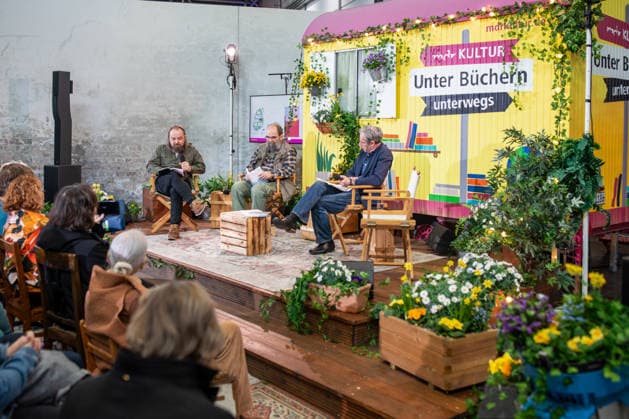 Leipzig - Lesebegeisterung in Leipzig: Buchmesse lockt tausende Besucher auf das Messegelände 21.03.2026¨Leipzig, Messe-Allee (Leipziger Messe)¨Fotografin: EHL Media Julia Tuncel Im Foto: Lesereihe Unter den Büchern unterwegs von MDR Kultur Am Samstagnachmittag zeigte sich die Leipziger Buchmesse auf dem Gelände der Leipziger Messe erneut als großer Publikumsmagnet. Am frühen Nachmittag herrschte ein deutlich erhöhtes Besucheraufkommen, zahlreiche Menschen strömten in die Hallen und durch die einzelnen Gänge. Im Verlauf des Tages nutzten tausende Literaturinteressierte die Gelegenheit, sich über Neuerscheinungen zu informieren, Lesungen zu besuchen und mit Autoren ins Gespräch zu kommen. Besonders stark frequentiert waren Copyright: xEHLxMedia JuliaxTuncelx 20260321_buchmesse-leipzig-jt_13