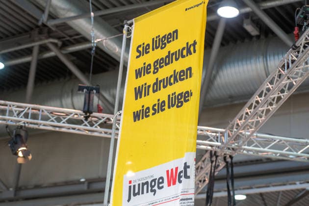 Leipzig - Volle Hallen zum letzten Messetag: Abschluss auf der Leipziger Buchmesse 22.03.2026¨Leipzig, Messe-Allee (Leipziger Messe) im Foto: Slogan Sie lügen wir gedruckt. Wir drucken wie sie lügen. der Zeitung junge Welt¨¨Am Sonntag hat die Leipziger Buchmesse noch einmal zahlreiche Besucher auf das Messegelände gelockt und einen lebendigen Abschluss des diesjährigen Events geboten. Besonders Familien, Literaturfans und Cosplay-Begeisterte nutzten den letzten Messetag, um durch die Hallen zu schlendern, Neuerscheinungen zu entdecken und Autorinnen und Autoren hautnah zu erleben. Neben gut besuchten Lesungen und Signierstunden stand vor allem der Austausch im Mittelpunkt: Gespräche über aktuelle gesellschaftliche T Copyright: xEHLxMedia Erik-HolmxLanghofx 20260322_buchmesse-leipzig-sonntag_32
