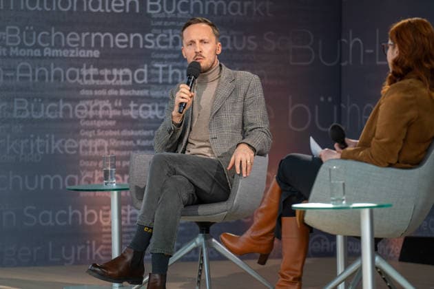 Leipzig - Volle Hallen zum letzten Messetag: Abschluss auf der Leipziger Buchmesse 22.03.2026¨Leipzig, Messe-Allee (Leipziger Messe) im Foto: Michal Hvorecky mit seinem Buch Dissident auf der Bühne von ARD, ZDF und 3sat in der Glashalle ¨Am Sonntag hat die Leipziger Buchmesse noch einmal zahlreiche Besucher auf das Messegelände gelockt und einen lebendigen Abschluss des diesjährigen Events geboten. Besonders Familien, Literaturfans und Cosplay-Begeisterte nutzten den letzten Messetag, um durch die Hallen zu schlendern, Neuerscheinungen zu entdecken und Autorinnen und Autoren hautnah zu erleben. Neben gut besuchten Lesungen und Signierstunden stand vor allem der Austausch im Mittelpunkt: Gespräche über aktuelle gesellschaftli Copyright: xEHLxMedia Erik-HolmxLanghofx 20260322_buchmesse-leipzig-sonntag_67