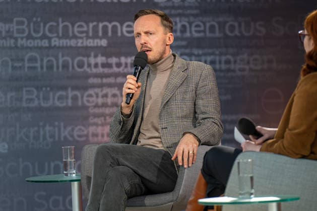 Leipzig - Volle Hallen zum letzten Messetag: Abschluss auf der Leipziger Buchmesse 22.03.2026¨Leipzig, Messe-Allee (Leipziger Messe) im Foto: Michal Hvorecky mit seinem Buch Dissident auf der Bühne von ARD, ZDF und 3sat in der Glashalle ¨Am Sonntag hat die Leipziger Buchmesse noch einmal zahlreiche Besucher auf das Messegelände gelockt und einen lebendigen Abschluss des diesjährigen Events geboten. Besonders Familien, Literaturfans und Cosplay-Begeisterte nutzten den letzten Messetag, um durch die Hallen zu schlendern, Neuerscheinungen zu entdecken und Autorinnen und Autoren hautnah zu erleben. Neben gut besuchten Lesungen und Signierstunden stand vor allem der Austausch im Mittelpunkt: Gespräche über aktuelle gesellschaftli Copyright: xEHLxMedia Erik-HolmxLanghofx 20260322_buchmesse-leipzig-sonntag_70