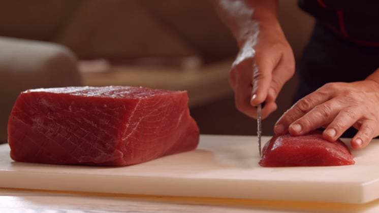Fresh raw bluefin tuna fillet being sliced by a chef on a board Tokyo, Tokyo, Japan R_EYUC260316B-1982598-01