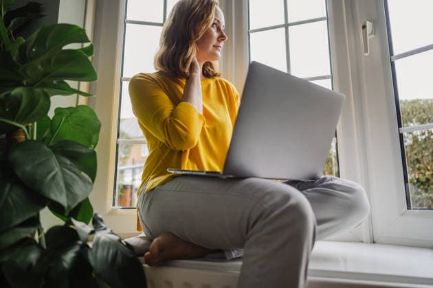 Entrepreneur working from home with laptop by window and indoor plant model released, Symbolfoto property released, IGEF00748