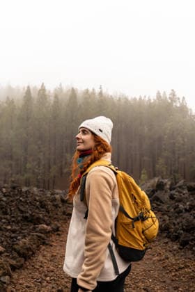 Hiker with backpack smiling in misty forest near Volcan Chinyero model released, Symbolfoto, AFVF09425