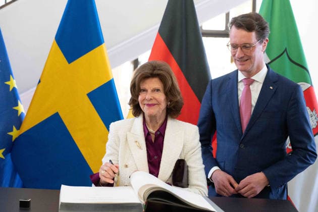 Koenigin SILVIA von SCHWEDEN, traegt sich in das goldene Buch der Landesregierung ein, Hendrik WUEST, Wüst, CDU, Ministerpraesident des Landes Nordrhein-Westfalen, begruesst Koenigin SILVIA von SCHWEDEN, in der Staatskanzleir in Duesseldorf am 23.03.2026
