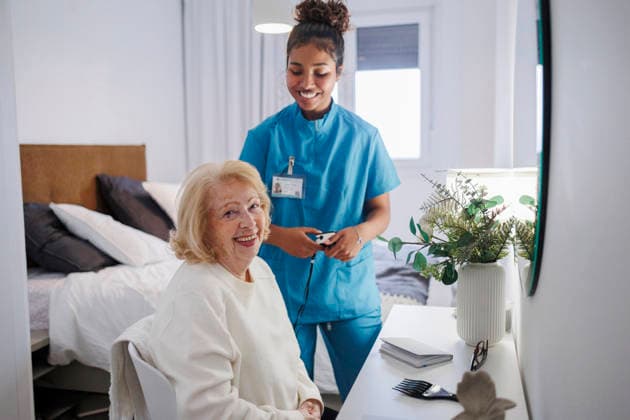 Nurse supporting elderly woman with reading at home in a relaxed setting model released, Symbolfoto property released, JCCMF14630