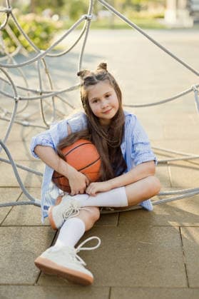 Child sitting with basketball at outdoor playground in summer sunlight model released, Symbolfoto, ONAF01187