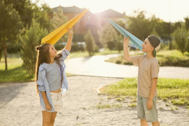 Kids playing with paper planes at a park on a sunny summer day model released, Symbolfoto, ONAF01189