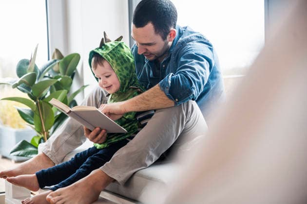 Father and son reading a book together at home in living room model released, Symbolfoto property released, UUF36526