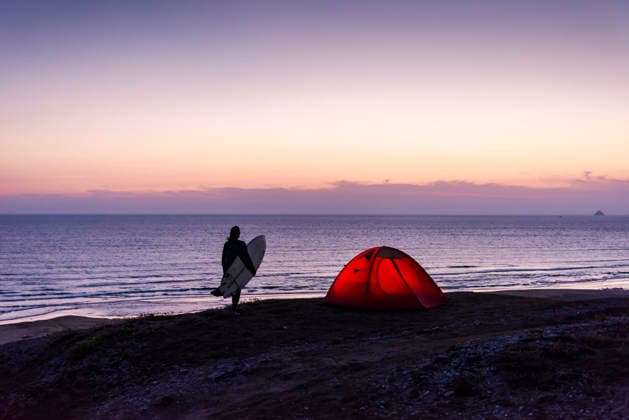Silhouette with surfboard and tent by the sea at sunset model released, Symbolfoto, UUF36537