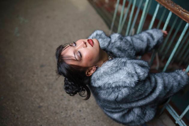 Fashionable woman in fur coat resting by shabby blue entrance outdoors model released, Symbolfoto property released, VCF01359