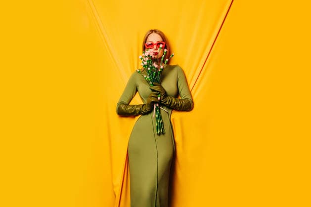 Stylish woman in green dress with floral bouquet on yellow background model released, Symbolfoto, VSNF04654