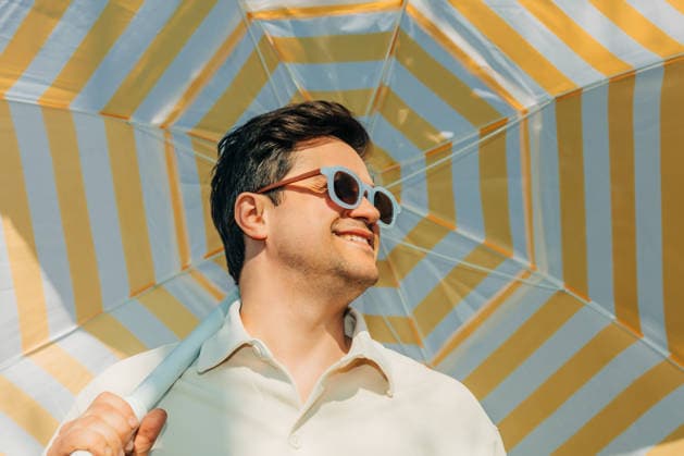 Smiling man with sunglasses under striped summer umbrella outdoors model released, Symbolfoto, VSNF04728