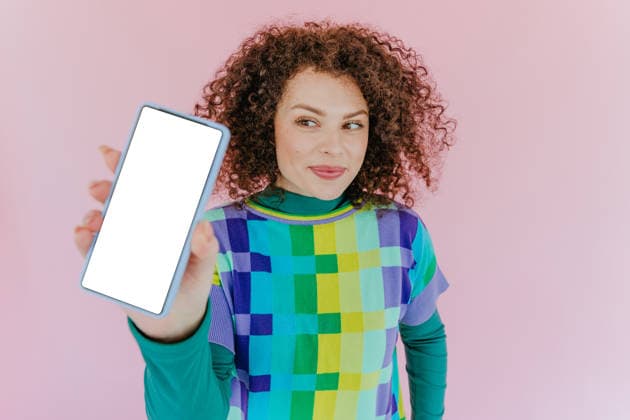 Smiling woman showing smartphone with blank screen on pink background model released, Symbolfoto property released, YTF04591
