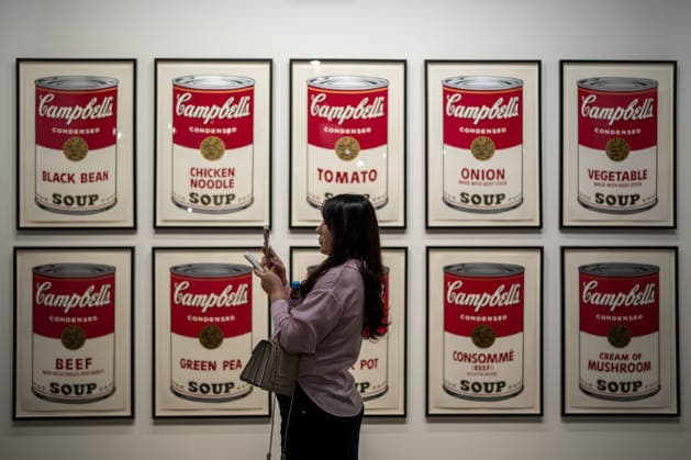 HONGKONG-ART ART-BASEL A woman taking a photo with her phone in front of Campbell s Soup Cans drawings at Art Basel 2026 in Hong Kong, March 26, 2026. NEXPHER Vernon Yuen HONG KONG