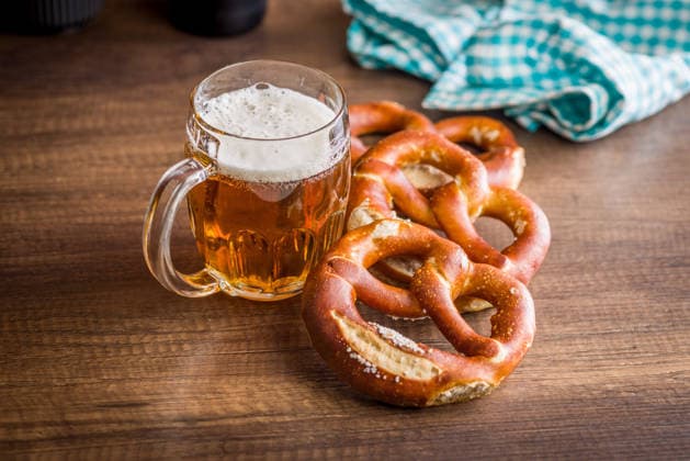 Bierkrug und weiche Brezeln auf einem rustikalen Holztisch. Oktoberfest-Snack und bayerische Kneipenküche Golden beer in a frothy mug paired with salt-topped soft pretzels on a rustic wooden table, evoking Oktoberfest and Bavarian pub tradition, casual dining, friendly gatherings and comforting snack moments. (License=RF) Copyright: xZoonar.com JirixHERAx 24824541