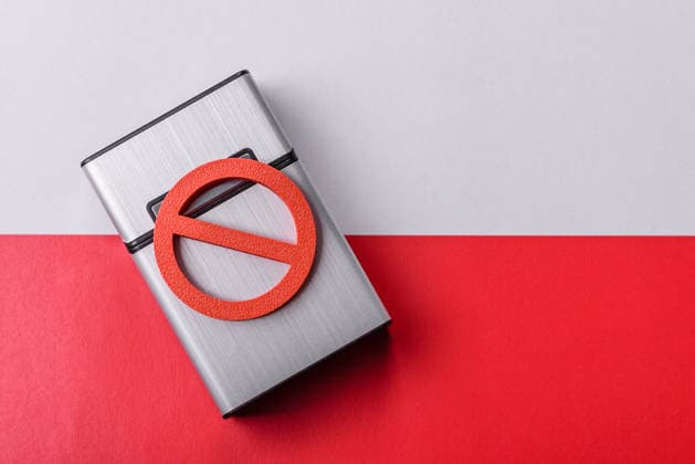 Eine Metallzigarettenbox mit einem Rauchverbotsschild symbolisiert eine schädliche Gewohnheit. Eine Zigarettenbox A metal cigarette box with a no smoking sign depicts a harmful habit, nicotine use, and the risk of cancer. A cigarette box and no smoking sign as a backdrop for your design. (License=RF) Copyright: xZoonar.com TetianaxChernykovax 24826235