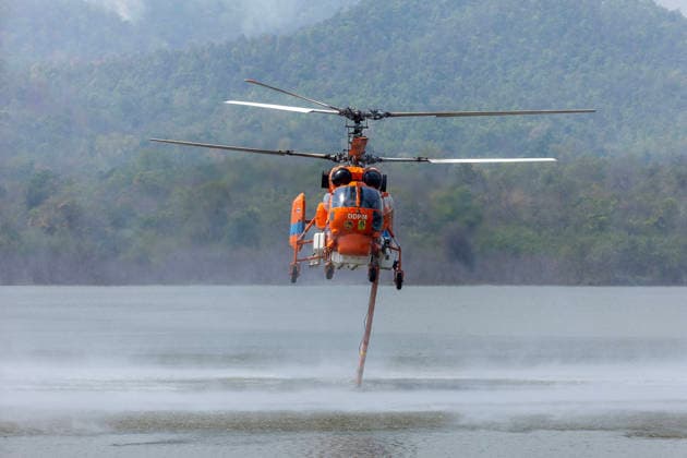 Helicopters Battle Wildfires in Chiang Mai, Thailand - 27 Mar 2026 A helicopter performs water pickup operations over a reservoir in Chiang Mai, northern Thailand, as part of aerial firefighting efforts against ongoing wildfires. A KA-32 helicopter from the Department of Disaster Prevention and Mitigation skims the water surface to collect water before heading to fire-affected forest areas amid hazy conditions caused by smoke and rising PM2.5 pollution. Chiang Mai Thailand Copyright: xPongmanatxTasirix xSOPAxImagesx PTASIRI270326R6II5773