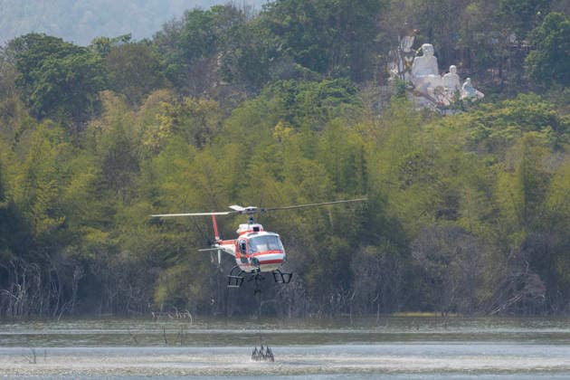 Helicopters Battle Wildfires in Chiang Mai, Thailand - 27 Mar 2026 A helicopter performs water pickup operations over a reservoir in Chiang Mai, northern Thailand, as part of aerial firefighting efforts against ongoing wildfires. An AS350 helicopter from the Ministry of Natural Resources and Environment skims the water surface to collect water before heading to fire-affected forest areas amid hazy conditions caused by smoke and rising PM2.5 pollution. Chiang Mai Thailand Copyright: xPongmanatxTasirix xSOPAxImagesx PTASIRI270326R6II6424