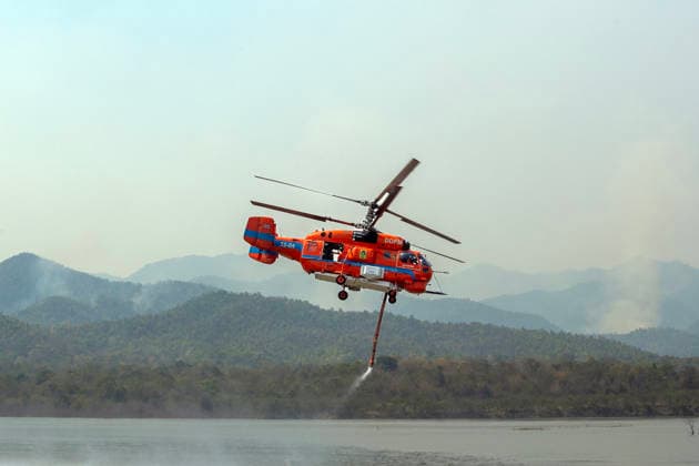 March 27, 2026, Chiang Mai, Thailand: A helicopter performs water pickup operations over a reservoir in Chiang Mai, northern Thailand, as part of aerial firefighting efforts against ongoing wildfires. A KA-32 helicopter from the Department of Disaster Prevention and Mitigation skims the water surface to collect water before heading to fire-affected forest areas amid hazy conditions caused by smoke and rising PM2.5 pollution. Chiang Mai Thailand  - ZUMAs197 20260327_aaa_s197_308 Copyright: xPongmanatxTasirix
