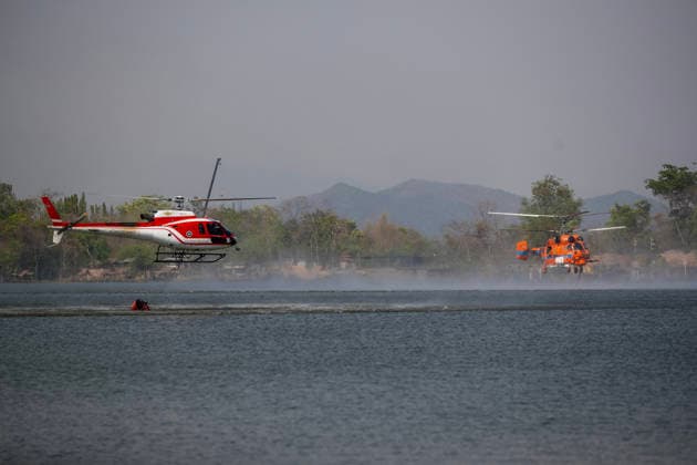 March 27, 2026, Chiang Mai, Thailand: Two helicopters perform water pickup operations over a reservoir in Chiang Mai, northern Thailand, as part of aerial firefighting efforts against ongoing wildfires. An AS350 helicopter from the Ministry of Natural Resources and Environment (left) and a KA-32 helicopter from the Department of Disaster Prevention and Mitigation (right) skim the water surface to collect water before heading to fire-affected forest areas amid hazy conditions caused by smoke and rising PM2.5 pollution. Chiang Mai Thailand  - ZUMAs197 20260327_aaa_s197_319 Copyright: xPongmanatxTasirix