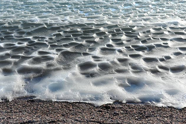 Creative Highlights World Gefrorene Uferlinie mit strukturierten, schmelzenden Eis- und Schneebildungen in der Nähe eines Kieselstrandes Frozen shoreline with textured melting ice and snow formations near a pebbled beach, illuminated by bright winter sunlight creating patterns and shadows across the icy surface. (License=RF) Copyright: xZoonar.com MikhailxOlykaynenx 24840537