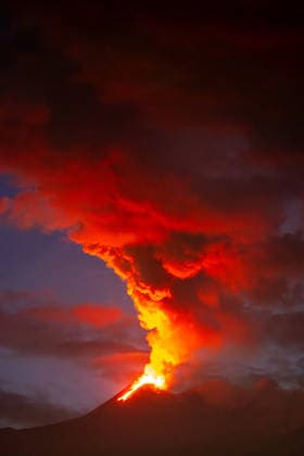 Creative Highlights World Ausbruch des Ätna mit einer dichten roten Rauchsäule A dense red smoke column and glowing lava burst from Mount Etnas crater, rising high into the twilight sky above the volcanic cone. (License=RF) Copyright: xZoonar.com DetlefxVoigtxinfo@gph-foto.dex 24843851