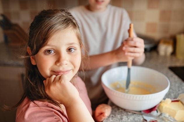 Girl smiling at camera in kitchen during baking, family cooking. Corby, England, United Kingdom CR_JNDO260328-1931300-01 ,model released, Symbolfoto