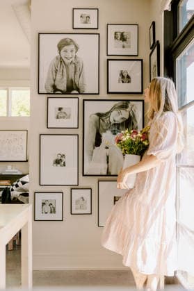 Woman admires gallery of framed portraits in her home Boise, Idaho, United States CR_PHZD260328-1975915-01 ,model released, Symbolfoto ,property released
