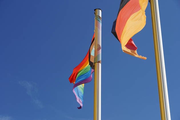 Progress-Pride-Flagge, Progressive Regenbogenfahne und Flagge der Bundesrepublik Deutschland an zwei Fahnenmasten nebeneinander, Symbol für Vielfalt, Toleranz und der Repräsentation von LGBTQIA+-Rechten, queere Menschen als Teil der Gesellschaft *** Progress Pride Flag, Progressive Rainbow flag and Flag the Federal Republic Germany to Two Flagpoles side by side, symbol for Diversity, Tolerance and the Representation from LGBTQIA On the right, queere People as Part the Company 1131608821