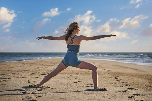 Eine Frau führt die Warrior 2 Virabhadrasana 2 Pose am Strand aus und genießt während ihrer Yoga Praxis den ruhigen Sonnenuntergang und die Meeresbrise A woman performs the Warrior 2 Virabhadrasana 2 pose on the beach, enjoying the calm sunset and ocean breeze during her yoga practice Copyright: imageBROKER DmitryxRukhlenko ibxdmr17218871.jpg ,model released, Symbolfoto ,property released