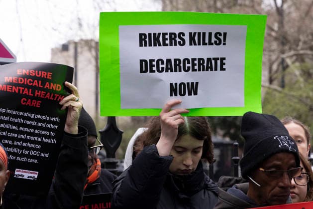 April 2, 2026, New York, New York, USA: Jails Action Coalition and HALT Solitary Campaign rally at City Hall after the recent deaths of two people in Department of Corrections (DOC) custody in New York City jails. A person participates in moment of silence mourning the deaths of Barry Cozart and John Price holding a sign that reads RIKERS KILLS! DECARCERATE NOW. Advocates call for City and State lawmakers to implement the Blueprint to End The Humanitarian Crises Of NYC Jails. New York USA - ZUMAr174 20260402_znp_r174_011 Copyright: xGinaxMxRandazzox