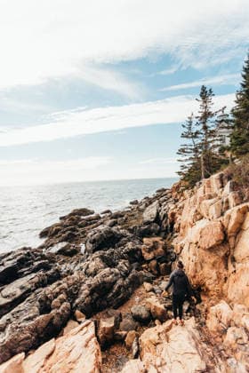 Young woman climbing rocky coast near Bass Harbor Light Station Tremont, Maine, United States R_XPQF260404-1991156-01 ,model released, Symbolfoto