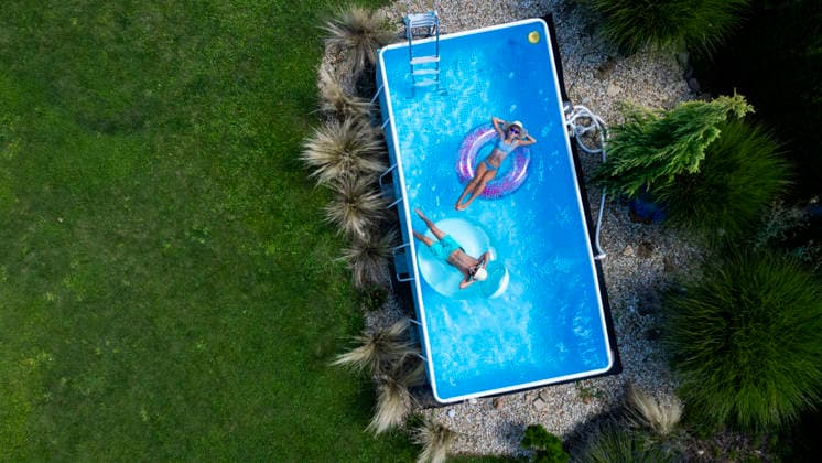 Two children relaxing on inflatable pool floats in backyard pool on summer day. Two children relaxing on inflatable pool floats in backyard pool on sunny summer day. Top view. model released