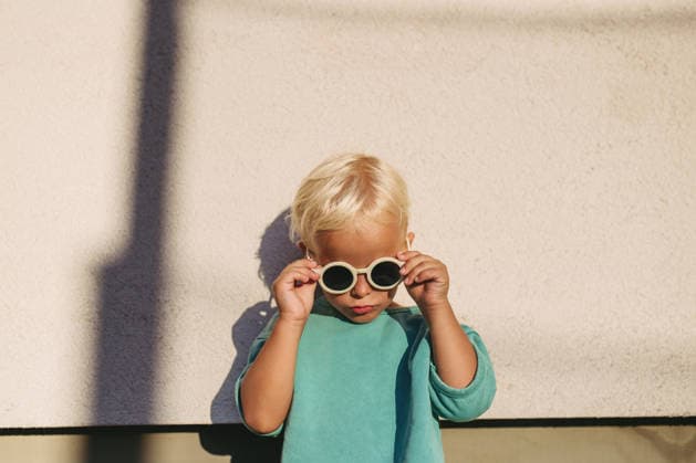 Smiling blond child wearing round sunglasses in warm sunlight. Smiling blond child wearing round sunglasses in warm sunlight. Summer season. model released