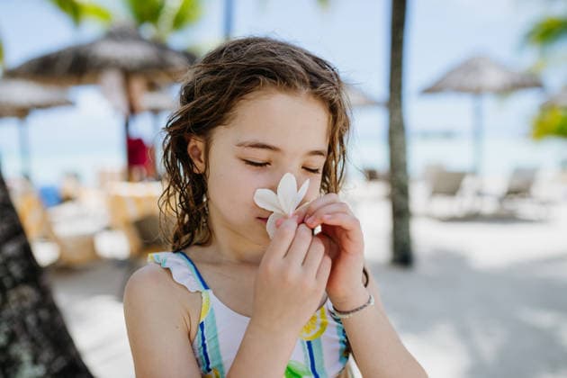 Happy child smelling tropical flower during family vacation at beach resort. Happy child smelling tropical flower during family vacation at beach resort. Summer holiday. model released