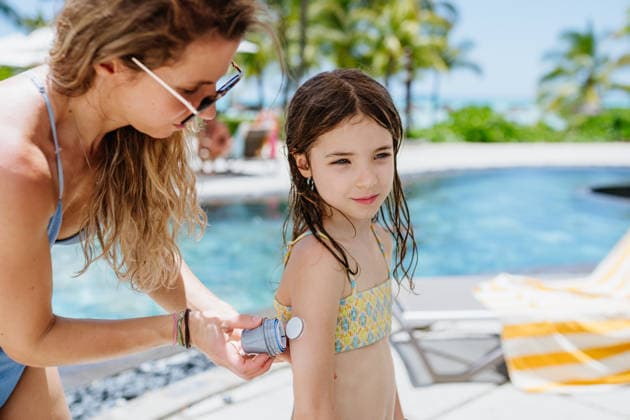 Mother changing glucose sensor for diabetic daughter by pool. Mother changing glucose sensor for diabetic daughter by pool during summer vacation. model released