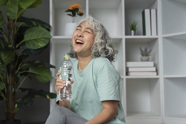 Glückliche Seniorin, die einen gesunden Lebensstil genießt, eine Wasserflasche in der Hand hält und in einer komfortablen häuslichen Umgebung lacht Happy senior woman enjoying a healthy lifestyle, holding a water bottle, and laughing in a comfortable home environment Copyright: imageBROKER WORAWEExMEEPIAN ibxiqx17170121.jpg ,model released, Symbolfoto ,property released