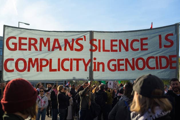 News Bilder des Tages #2 April 11, 2026, Berlin, Berlin, Germany: Protestors hold a banner writing Germans Silence Is Complicit in Genocide , on April 11, 2026 in Berlin, Germany. The monthly mass demonstration for Palestine took place this April in Berlin with the presence of Palestininans and allies protesting agains the attacks in Gaza, Lebabon and Iran from Israel and United States. Berlin Germany  - ZUMAk201 20260411_zip_k201_005 Copyright: xNikosxKanistrasx