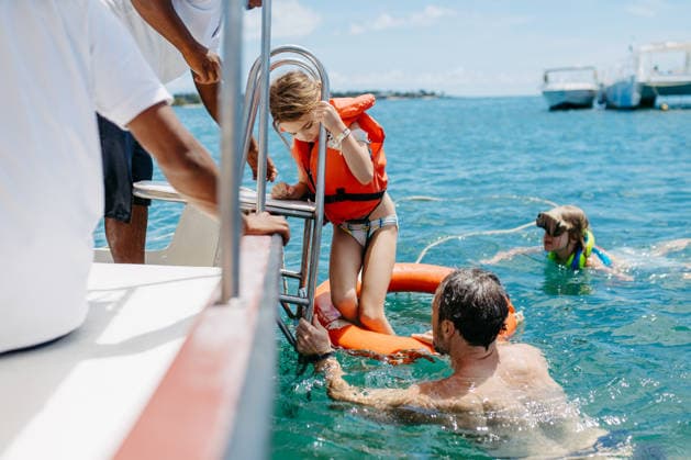 Family swimming and snorkeling near boat during tropical vacation. Family swimming and snorkeling near boat during tropical vacation. Summer holiday. model released