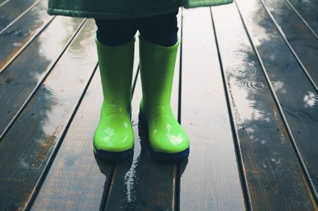 Nahaufnahme der Beine eines Kindes, das auf einer Veranda steht und grüne Gummistiefel und Regenmantel trägt. Regenstiefel in hellgrüner Farbe Closeup of legs of kid standing on a porch wearing green wellies and raincoat. Rain boots in bright green color Copyright: imageBROKER PrzemekxKlos ibxiqx16931953.jpg ,model released, Symbolfoto ,property released