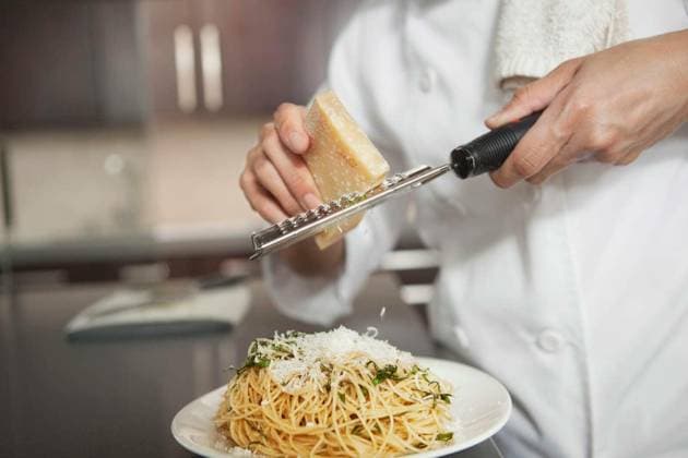 Chef Grating Cheese Onto Pasta In Kitchen - Midsection of female chef grating cheese onto pasta in kitchen model released Symbolfoto Copyright: xmoodboardx Panthermedia75454998.jpg