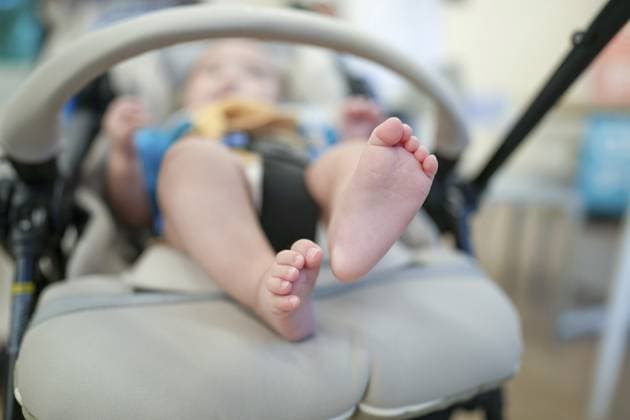 Ein Baby sitzt mit erhobenen Füssen in einem Kinderwagen. Der Kinderwagen ist grau und hat einen blauen Griff A baby is in a stroller with his feet up. The stroller is grey and has a blue handle Copyright: imageBROKER YujixZenda ibxiqx17129084.jpg ,model released, Symbolfoto ,property released