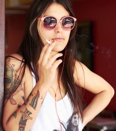 Shot of a beautiful young tattooed woman smoking a cigarette while listening to music. (License=RF) ,model released, Symbolfoto  Copyright: xZoonar.com KasperxRavlox 18323065 ,model released, Symbolfoto ,property released