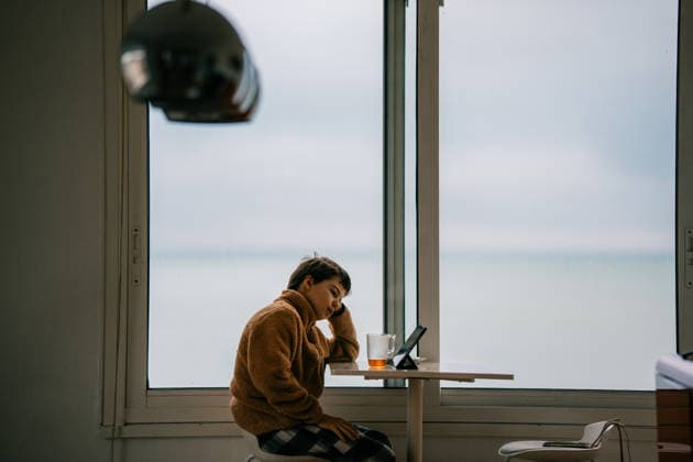 Teen sits by window looking out at sea, using a tablet Étretat, Normandy, France CR_UJEL260410-1997918-01 ,model released, Symbolfoto